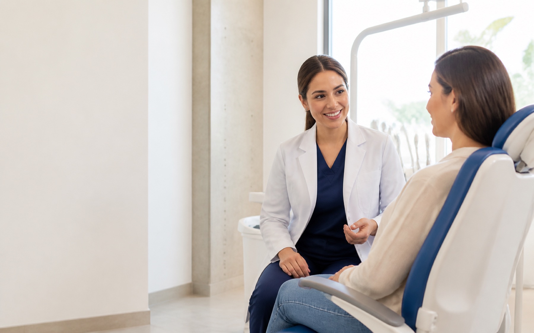 Profesional dental conversando con una paciente en una clínica luminosa
